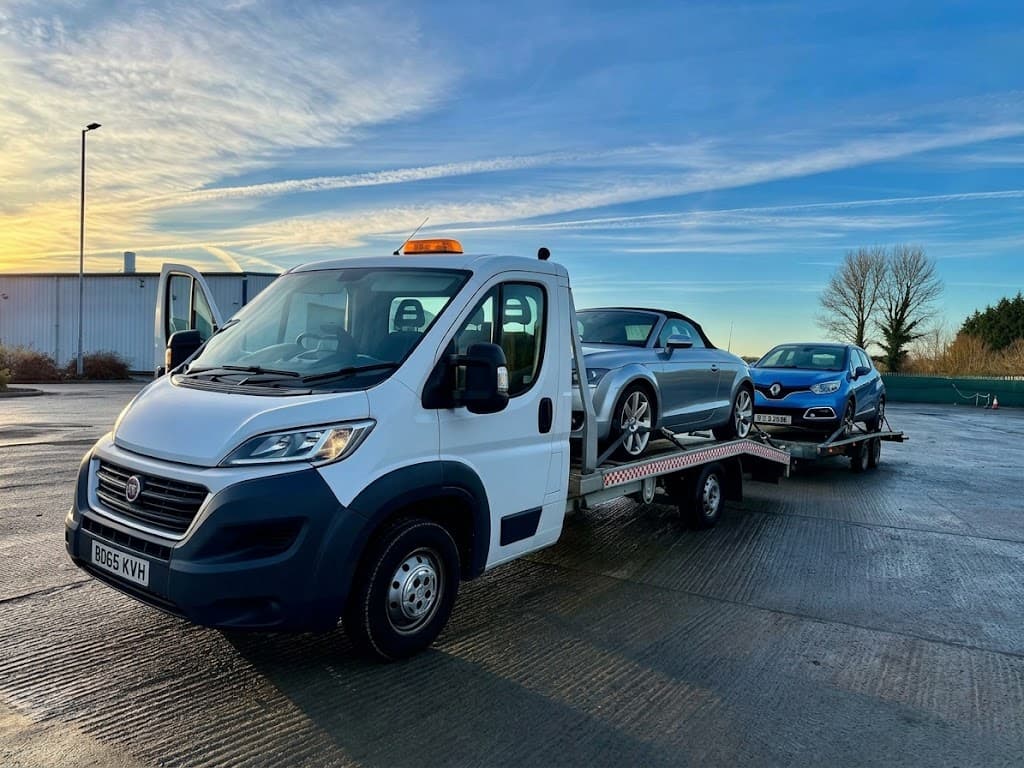 A white recovery truck carrying an Audi convertible and a Renault on a trailer