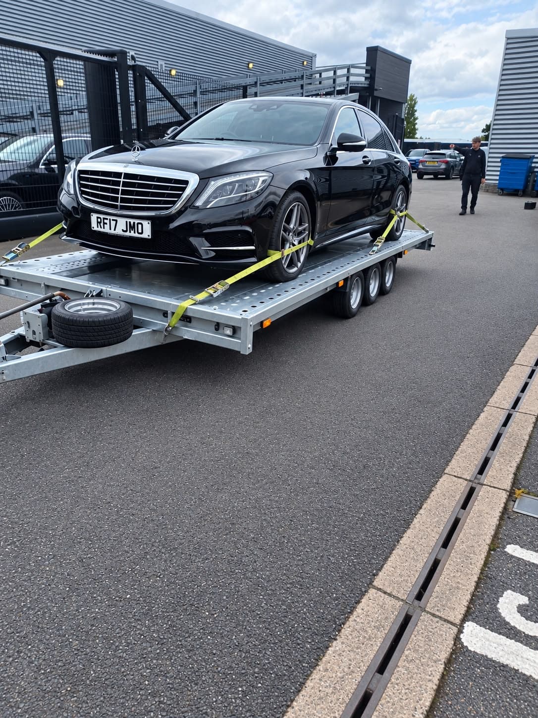 A black Mercedes saloon strapped onto a car transporter trailer